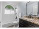 Bathroom with white tile, granite counters, dark cabinets, and a tub with a shower at 1366 S Vine St, Denver, CO 80210