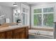 Bathroom vanity featuring a large mirror, wood cabinets, bright windows, and a soaking tub at 1366 S Vine St, Denver, CO 80210