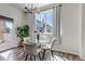 Bright dining area features a glass table, white chairs, modern lighting fixture, and a large window providing plenty of natural light at 1841 S Dunkirk St # 101, Aurora, CO 80017