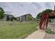 Large grassy backyard enclosed with wooden fence, accessible via red stairs from the deck at 2253 E 100Th Pl, Thornton, CO 80229