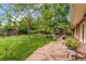 An expansive backyard with mature trees, well maintained lawn, sheds, and a stone patio with seating at 2775 Crabapple Rd, Golden, CO 80401