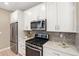 Modern kitchen with stainless steel appliances, white cabinets, and gray backsplash at 239 W Jamison Ct, Littleton, CO 80120