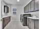 Modern laundry room with gray cabinetry, sink, light countertops, and stainless washer and dryer at 10492 Willowwisp Way, Highlands Ranch, CO 80126