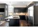 Open kitchen with black cabinetry, stainless appliances, island with seating, and fireplace in living area at 336 E 1St Ave # 209, Denver, CO 80203