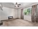 A cozy living room with neutral carpeting, a ceiling fan, and a large window dressed with patterned curtains at 1979 Beeler St, Aurora, CO 80010