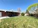 Spacious, level backyard featuring lush lawn, brick house, covered patio, mature trees, and landscaping at 2274 S Newton St, Denver, CO 80219