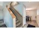 A carpeted staircase with wood railing leads to a dining area with hardwood style floors at 2900 Purcell St # I4, Brighton, CO 80601
