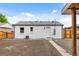 Back of white painted home with modern gutters, brick foundation, and privacy fence at 851 S Eliot St, Denver, CO 80219