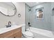 Modern bathroom with wood vanity, updated faucet, new lighting, and tub at 851 S Eliot St, Denver, CO 80219