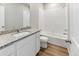 Bright bathroom featuring granite countertop, white vanity, and a tub with white tile surround at 869 Sawdust Dr, Brighton, CO 80601