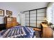 Comfortable bedroom featuring a bed, study area with a desk, and a closet with sliding panel doors at 3550 S Harlan St # 174, Denver, CO 80235
