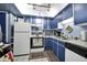 Efficient kitchen with bright blue cabinetry and white appliances, offering a clean and functional space at 3550 S Harlan St # 174, Denver, CO 80235