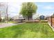 Expansive backyard featuring a lush lawn, mature tree, deck, and convenient shed at 5962 S Sheridan Way, Littleton, CO 80123