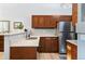 Well-lit kitchen with stainless steel refrigerator, wood cabinetry, light countertops, and modern faucet at 1355 S Ulster St, Denver, CO 80231