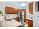 Bright kitchen featuring stainless steel refrigerator, wood cabinetry, light countertops, and modern lighting at 1355 S Ulster St, Denver, CO 80231