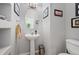 Stylish powder room with pedestal sink, decorative mirror, and neutral color palette, offering a fresh and modern touch at 1355 S Ulster St, Denver, CO 80231