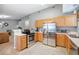 Well-lit kitchen featuring stainless steel appliances, light wood cabinets, and an adjacent living space at 11620 W 62Nd Pl # 201, Arvada, CO 80004