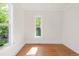 Sunny bedroom with warm hardwood floors boasts leafy backyard views from two large windows at 539 Baker St, Longmont, CO 80501