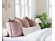 Bright bedroom with luxury bedding, pillows, and natural light from the window at 539 Baker St, Longmont, CO 80501