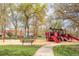 Colorful red playground set with swings and slides in a grassy park area at 539 Baker St, Longmont, CO 80501