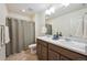 Bathroom featuring a double vanity with brown cabinets, white countertops, and a neutral-colored shower curtain at 1107 Sunrise Dr, Brighton, CO 80603