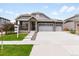 Charming home featuring a stone-accented entrance, gray siding, a three-car garage, and a well-manicured lawn at 17247 E 103Rd Ave, Commerce City, CO 80022