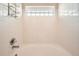Clean bathtub with a tiled surround and glass block window, creating a relaxing and bright bathing experience at 3205 S Walden Ct # H, Aurora, CO 80013