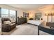 Bedroom featuring an oversized chair, large windows, gray dresser, and cozy bedding at 3205 S Walden Ct # H, Aurora, CO 80013