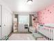Well-lit bedroom with closet, pink accent wall with strawberry design, crib and furniture at 8705 W Berry Ave # 204, Littleton, CO 80123