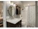 Bathroom features a dark vanity cabinet, a modern round mirror, and a shower with a decorative curtain at 3207 Opal Ln, Superior, CO 80027