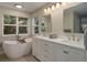 Bright bathroom featuring a soaking tub with views from the window and double sink vanity with white cabinets at 3207 Opal Ln, Superior, CO 80027
