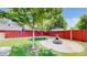 Well-maintained backyard with a grassy area, a fire pit, and a red wooden fence at 8774 Princeton St, Westminster, CO 80031