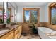 Elegant bathroom with dual vanities, wood cabinets, and a large soaking tub with nature views at 4446 Songbird Ln, Evergreen, CO 80439