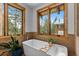 Bright bathroom features a soaking tub with views of the surrounding pine trees at 4446 Songbird Ln, Evergreen, CO 80439