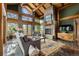 Bright living room featuring wood beams, a stone fireplace, and access to outdoor deck at 4446 Songbird Ln, Evergreen, CO 80439