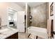 Bathroom featuring a tiled shower and tub combination, vanity with granite countertops, and a view into the laundry room at 4820 S County Road 137, Bennett, CO 80102