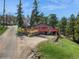 Spacious home with a large red deck, ample parking and natural surroundings on a sunny day at 3439 Burnham Dr, Kittredge, CO 80457