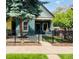 Charming blue house with a black wrought iron fence, well-manicured lawn, and mature trees for shade at 269 Delaware St, Denver, CO 80223