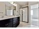 Elegant bathroom featuring double sinks, sleek black cabinetry, and a glass-enclosed shower at 6834 Merseyside Ln, Castle Pines, CO 80108