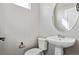 Bathroom boasts a pedestal sink, oval mirror, and a white toilet against light gray walls at 6834 Merseyside Ln, Castle Pines, CO 80108