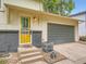 Close-up of the home's yellow front door and gray brick facade, leading to the gray garage at 12991 E Idaho Dr, Aurora, CO 80012