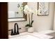 Close up of stylish bathroom featuring a black faucet, marble countertop, decorative mirror, and plant accent at 1940 W 101St Ct, Thornton, CO 80260