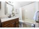 Bright bathroom featuring a tiled tub/shower, decorative mirror, stylish vanity with a marble countertop, and neutral-colored walls at 1940 W 101St Ct, Thornton, CO 80260