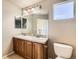 Well-lit bathroom featuring double sinks, wood vanity, and a bright window at 13018 Niagara Way, Thornton, CO 80602