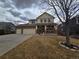 Two story home with brick and tan exterior, a spacious driveway, and covered front porch at 13018 Niagara Way, Thornton, CO 80602