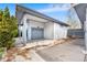 A white, detached garage with a gray door featuring a covered side area with natural light at 415 Lamar St, Lakewood, CO 80226