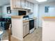 Cozy kitchen features white cabinets, appliances, and a breakfast bar open to the living area at 14413 E Jewell Ave # 201, Aurora, CO 80012