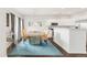 Open-concept dining area with a rustic wood table, upholstered chairs, and a blue patterned rug adjacent to the kitchen at 8944 Fox Dr # 203, Thornton, CO 80260