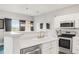 Kitchen area featuring stainless steel appliances, white cabinets, and a view of the dining area at 8944 Fox Dr # 203, Thornton, CO 80260