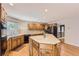 Well-lit kitchen featuring wood cabinets, an island, a double sink, and tile backsplash at 3480 S Dayton St, Denver, CO 80231